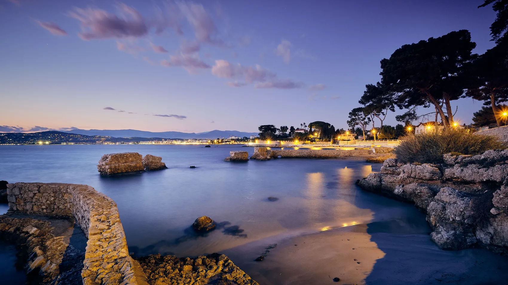 Le littoral à la tombée de la nuit, lumières se reflétant sur l'eau